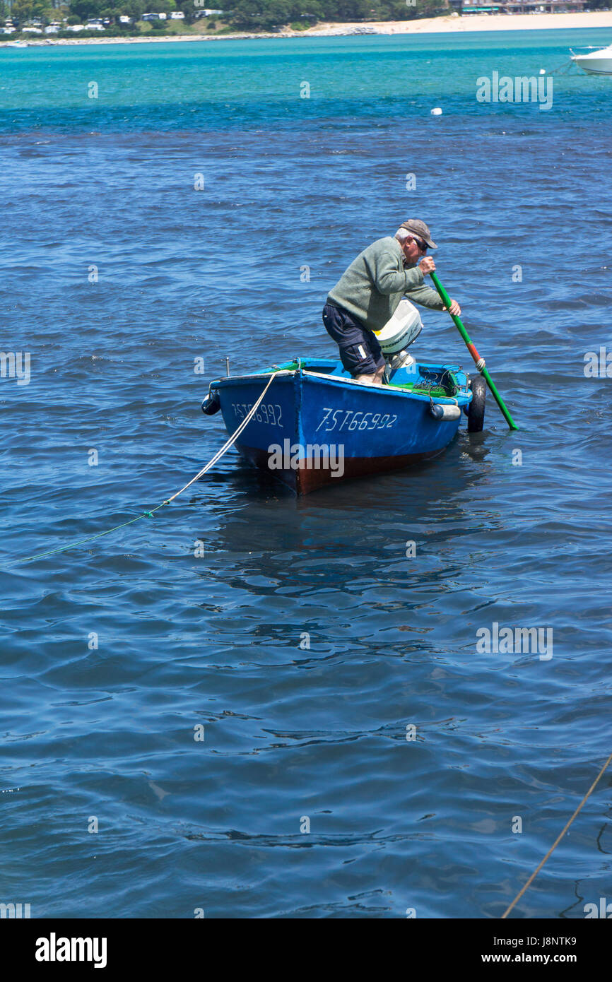 Ein älterer Mann Manöver sein kleine Boot mit einem Ruder. Stockfoto