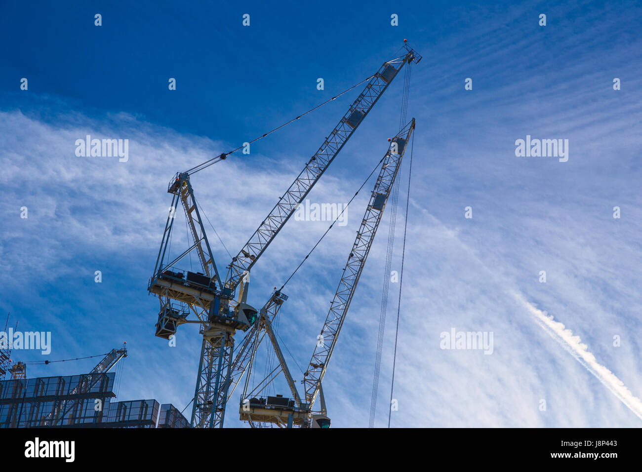 Baukräne gegen blauer Morgenhimmel mit flauschigen Wolken Stockfoto