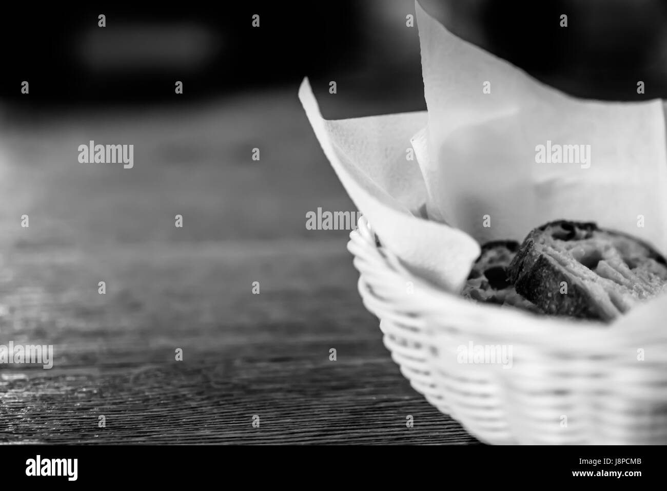 Brotscheiben in den Korb mit unscharfen Holztisch Hintergrund. Schwarz und weiß. Stockfoto
