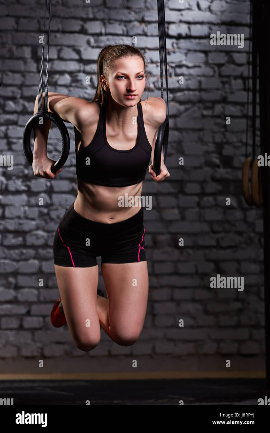Bild von schöne junge sportliche Frau in der schwarzen Sportwear Übung Klimmzüge mit Gymnastik Ringe. Stockfoto