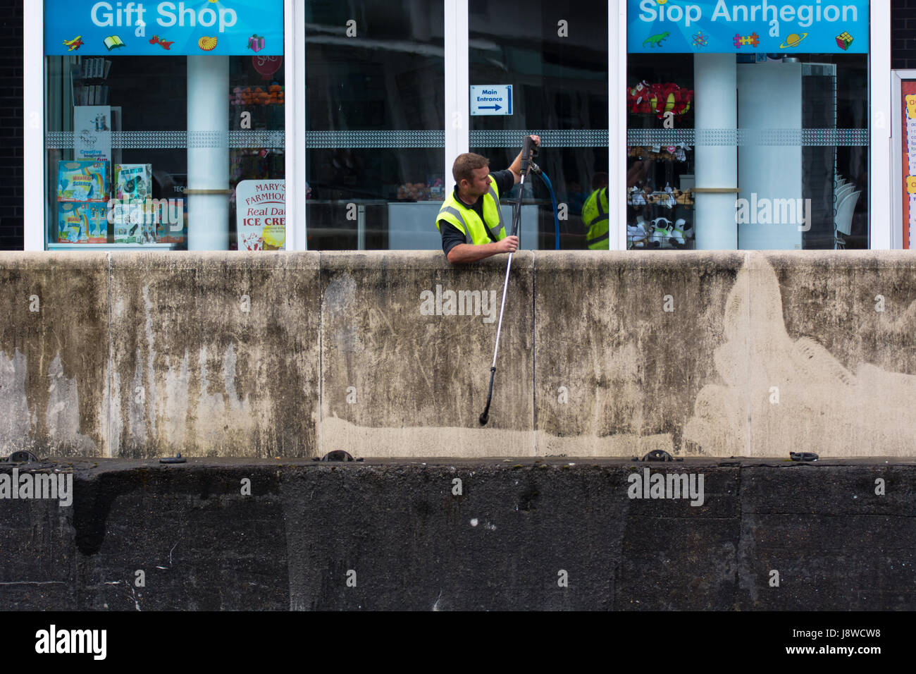 CARDIFF, UK - 29. Mai 2017 Arbeiter mit Druck Jet, saubere Wand. Der Mensch nutzt Hochdruckreiniger Schmutz aus Beton rund um Meerjungfrau Schlüssel entfernen Stockfoto
