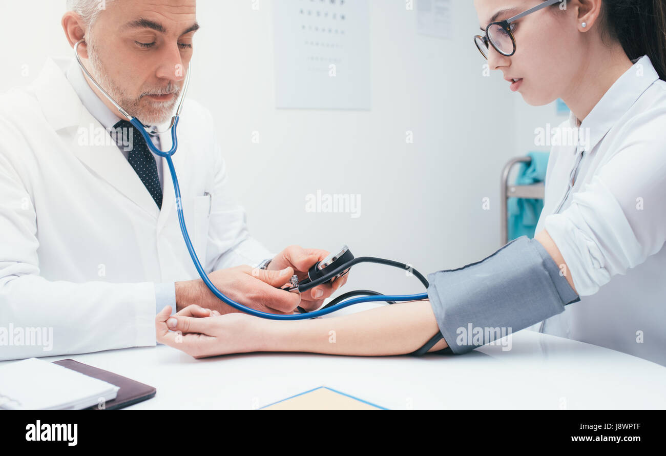 Zuversichtlich Arzt überprüft Blutdruck eines Patienten, misst er Herz Impulse mit einem Blutdruckmessgerät, Gesundheitswesen und Diagnostik-Konzept Stockfoto