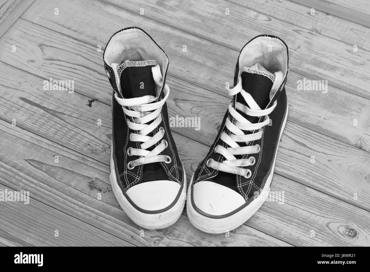 Monochrom schwarz / weiß Grunge Holz Hintergrund mit Vintage Canvas Sneaker Stockfoto
