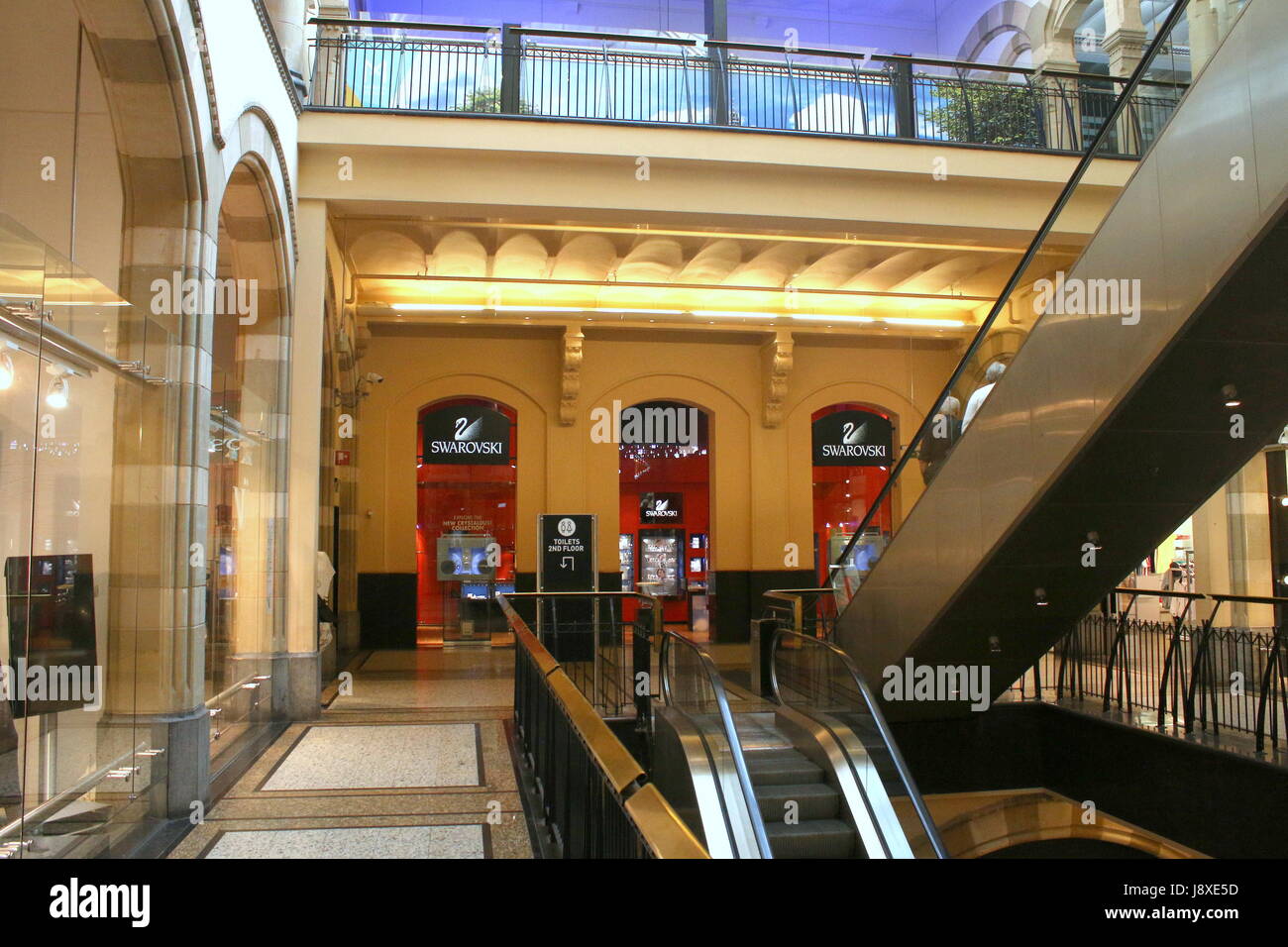 19. Jahrhundert Neo-gotischen Magna Plaza Einkaufszentrum am Nieuwezijds Voorburgwal, Amsterdam, Niederlande. Innenraum mit Swarovski Boutique.and Rolltreppen. Stockfoto