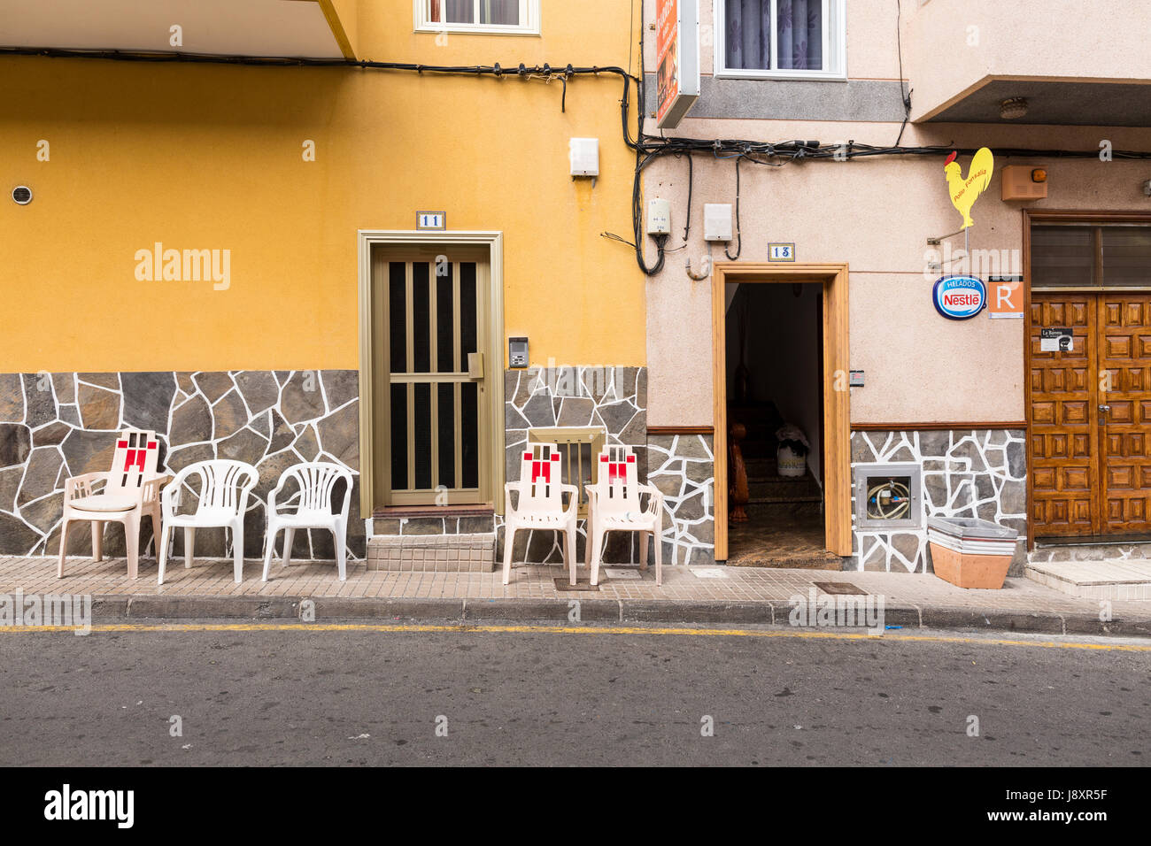 Zeile der leere Plastikstühle auf dem Bürgersteig vor Häusern und einem Restaurant in Fonsalia, Teneriffa, Kanarische Inseln, Spanien Stockfoto