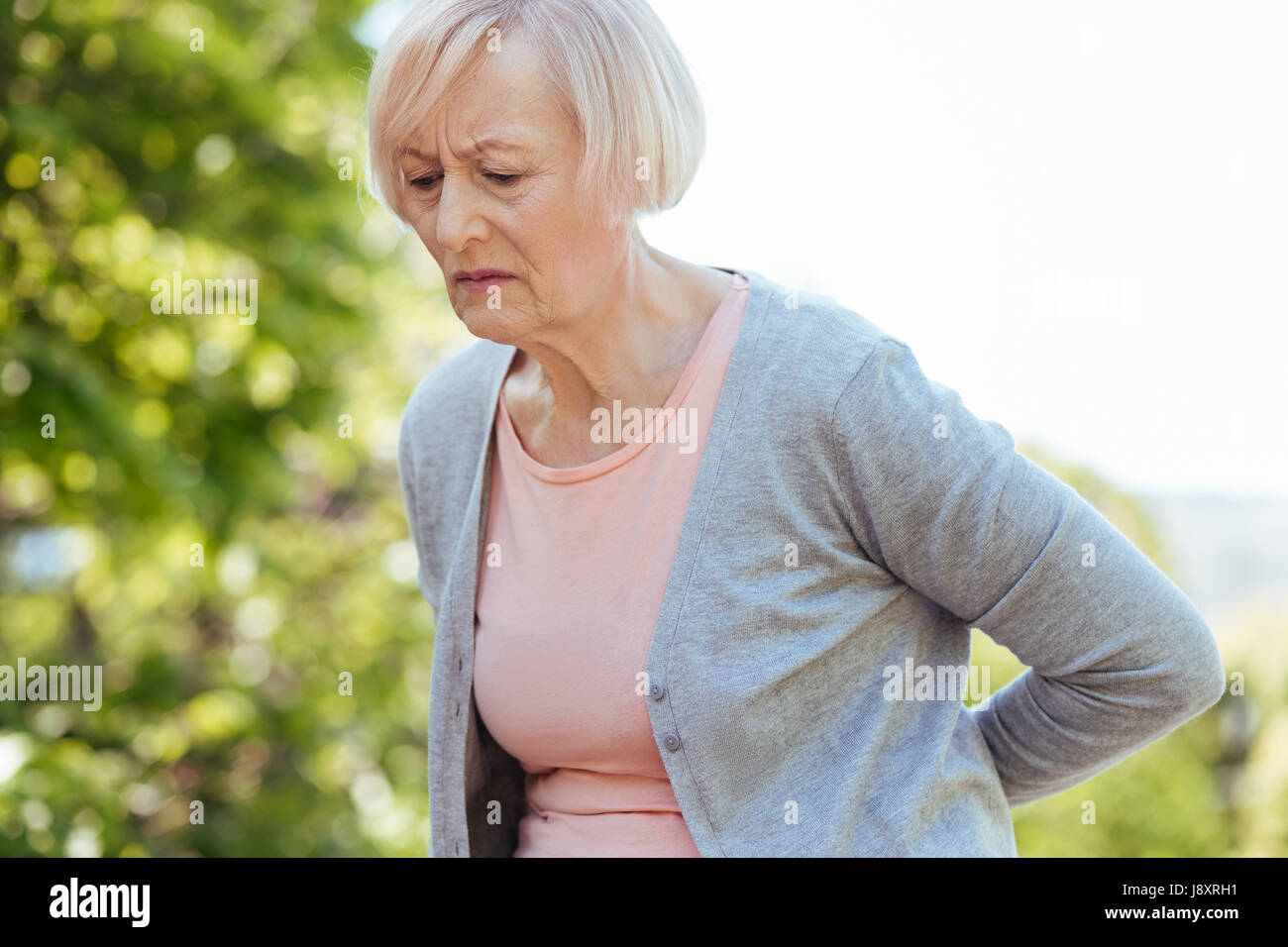 Frustrierte Rentner leiden unter Schmerzen im Rücken im freien Stockfoto