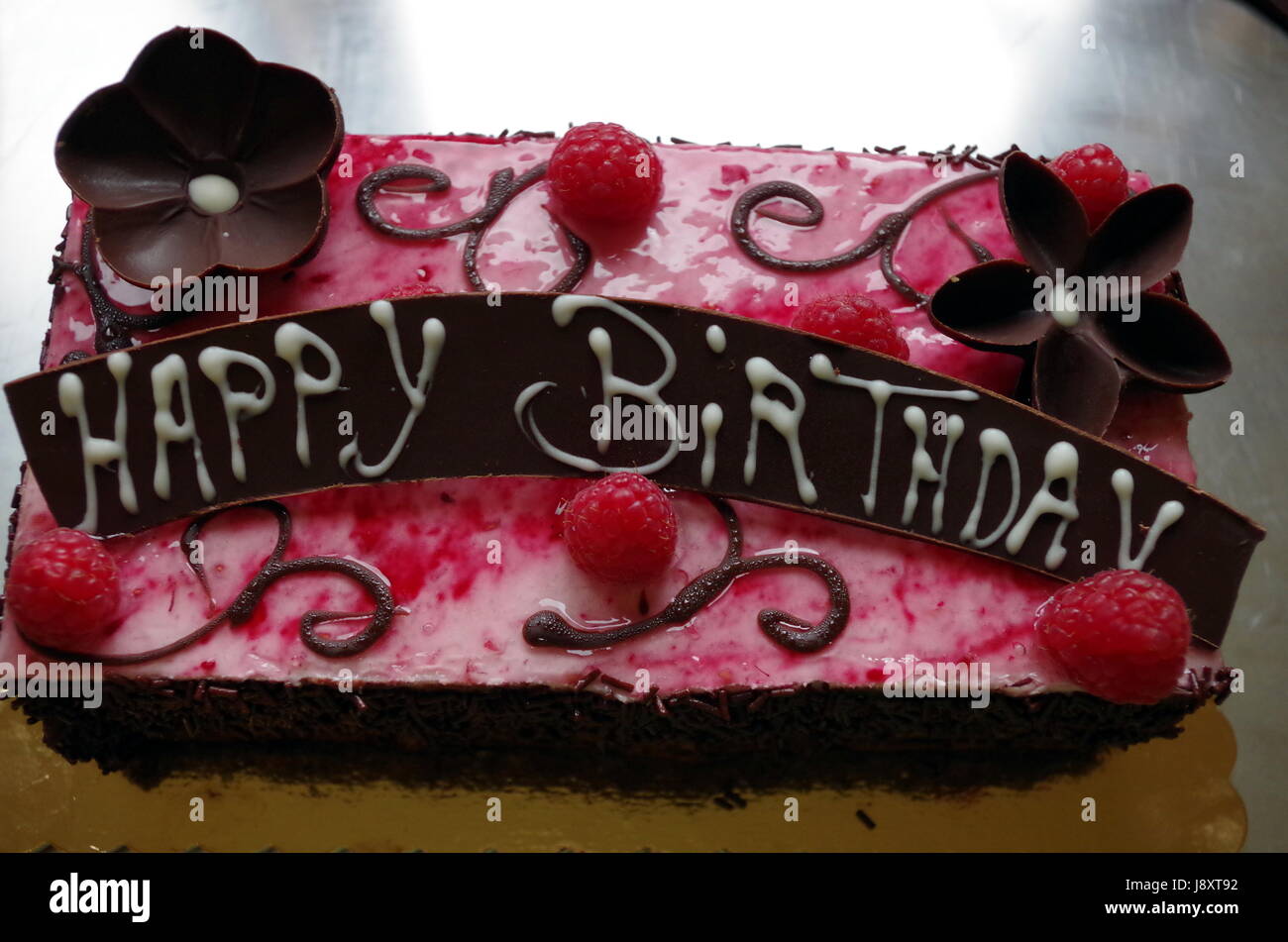 Schokolade Geburtstagskuchen mit Schokolade Blume und Himbeer Dekorationen und eine Schokolade HAPPY BIRTHDAY zu unterzeichnen. Stockfoto
