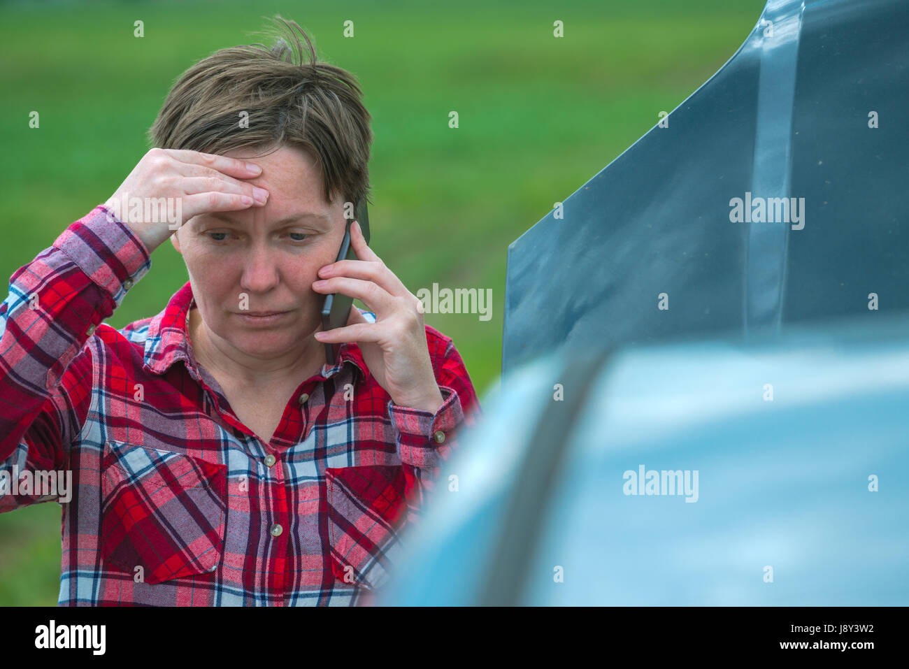 Unglücklich frustriert weibliche aufrufenden Kfz-Mechaniker-Werkstatt mit Handy aus Land Feldweg Stockfoto