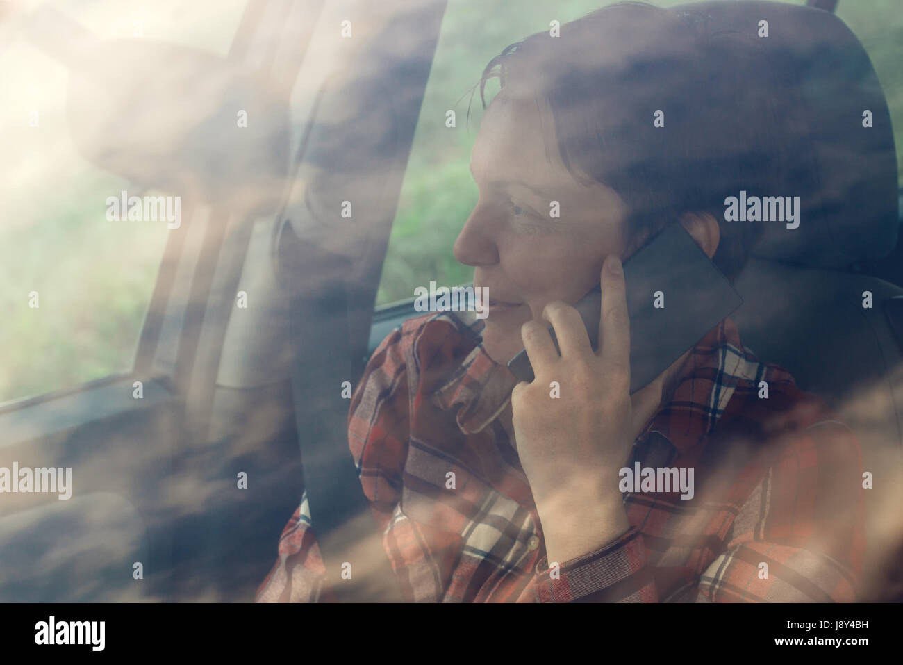 Lächelnde Frau telefonieren mit Handy im Auto, zufrieden Erwachsene weibliche Person während Telefongespräch Stockfoto