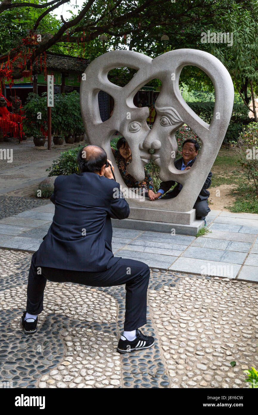 Guilin, China.  Elephant Trunk Hill Park.  Mann Skulptur fotografiert zwei Freunde hinter modernen aus Liebe. Stockfoto