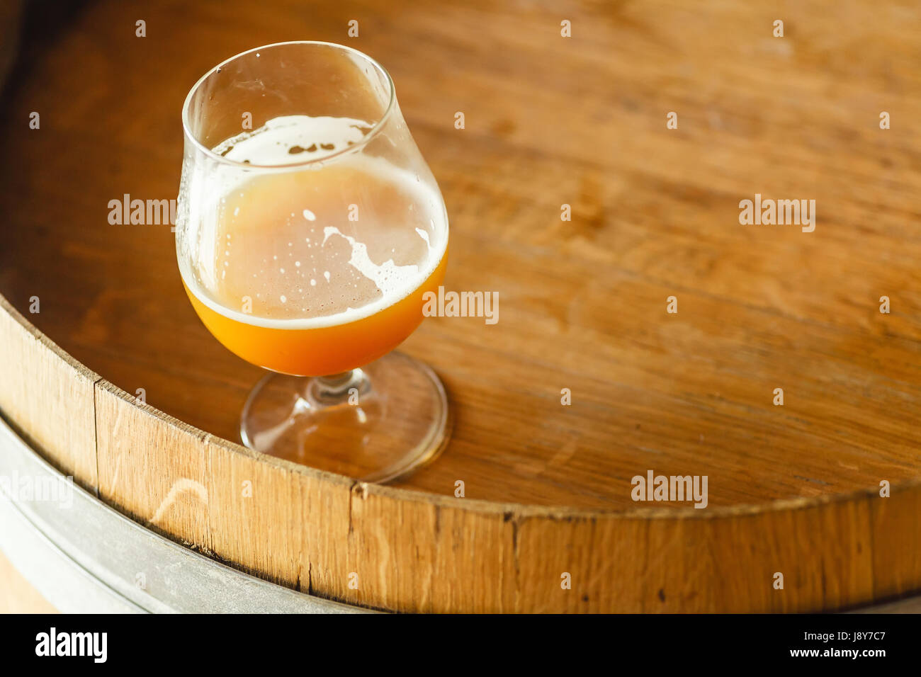 Glas Weizen Bier stehend auf einem Holzfass in einer Brauerei Stockfoto