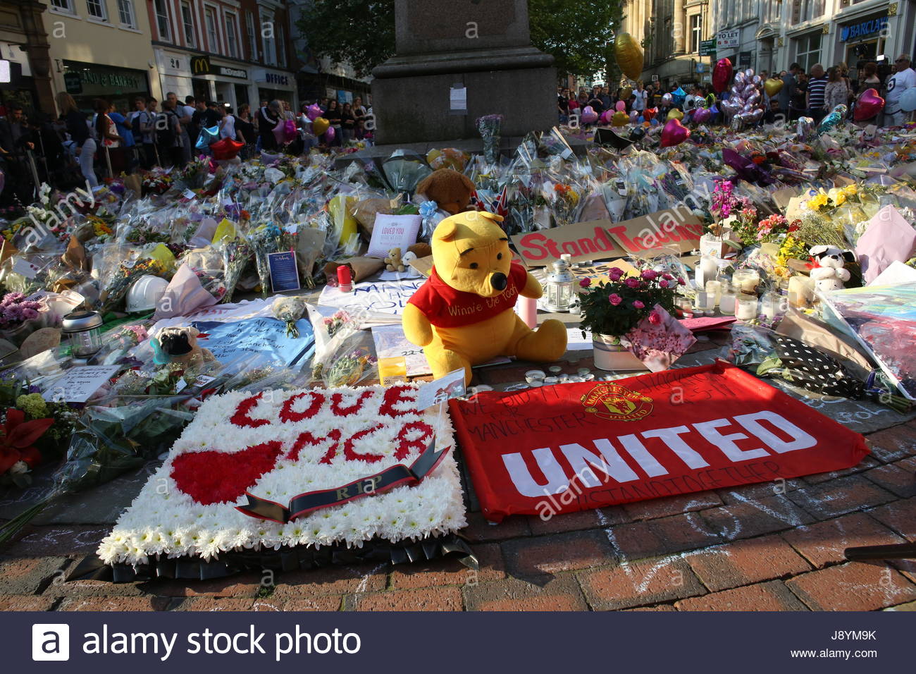 Ein Teddybär, ein rotes Herz und Blumen bilden eine Hommage an die Opfer der Bombardierung Mancheter. Stockfoto