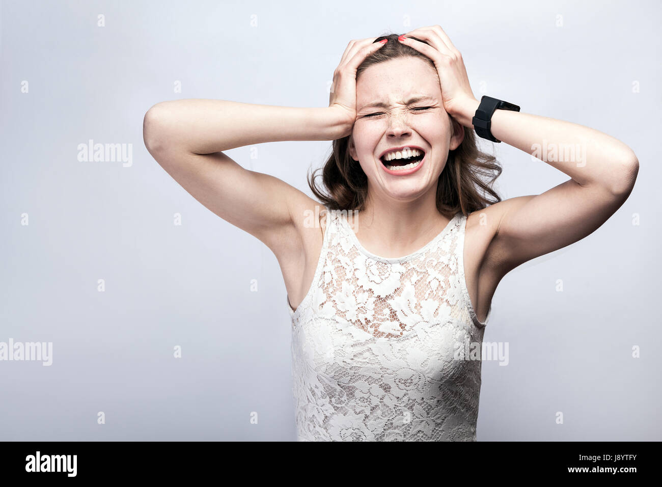 Porträt der schönen Frau mit Sommersprossen und weißes Kleid und Smartwatch mit Kopfschmerzen Schmerzen auf Silber grau hinterlegt. Gesundheitswesen und Medizin Konzeptionierung Stockfoto