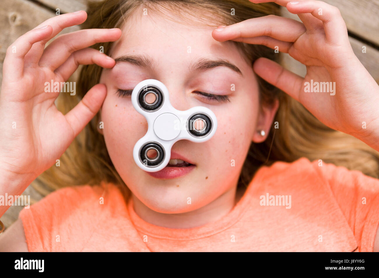 Weibliche Teenager spielen mit zappeln Spinner Spinnerei Spielzeug auf ihre Nase Model Release: Ja. Property Release: Nein. Stockfoto