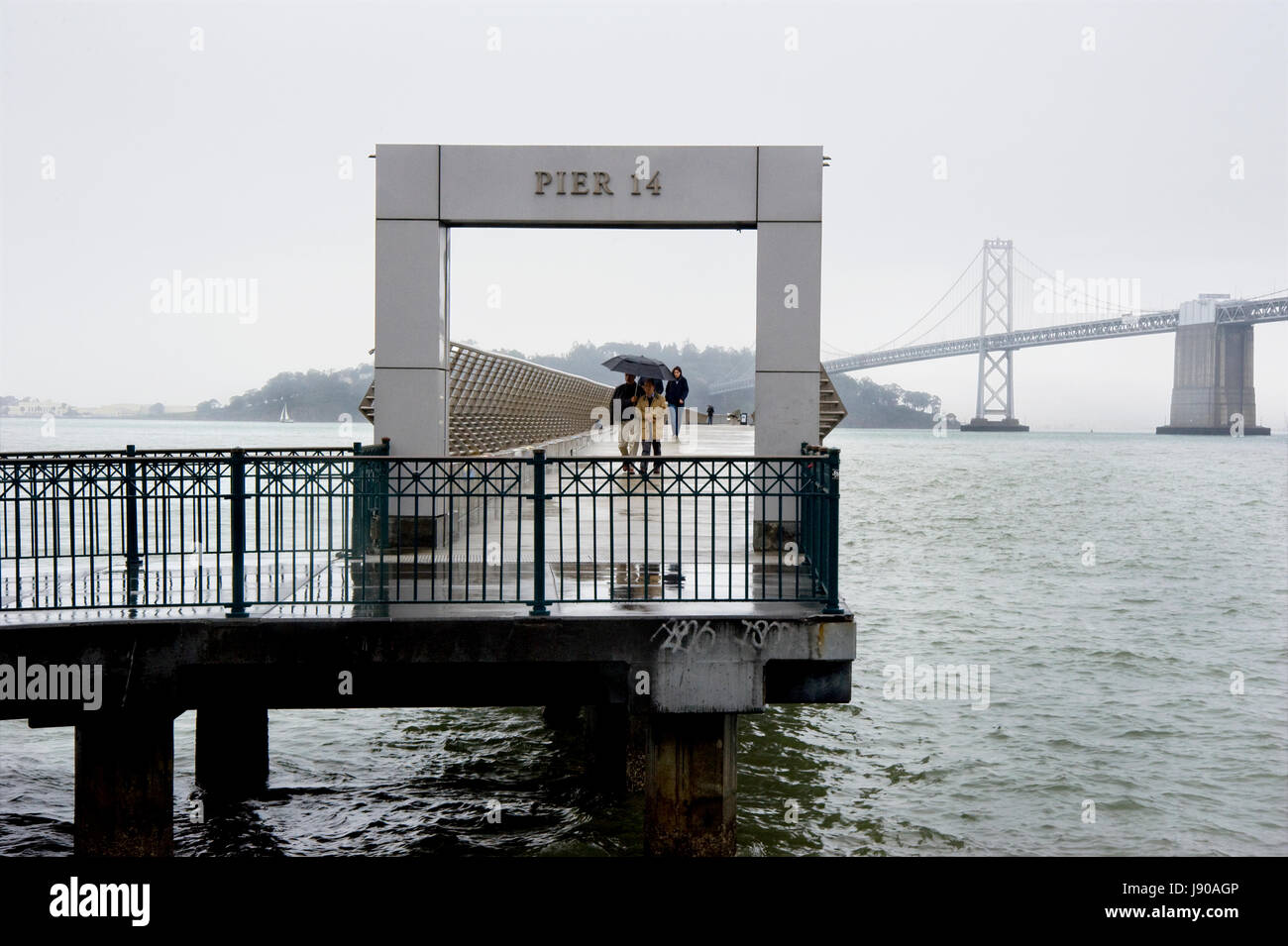 Menschen, die ein Spaziergang am Pier 14 an der Wharf in San Francisco an einem regnerischen Tag Stockfoto