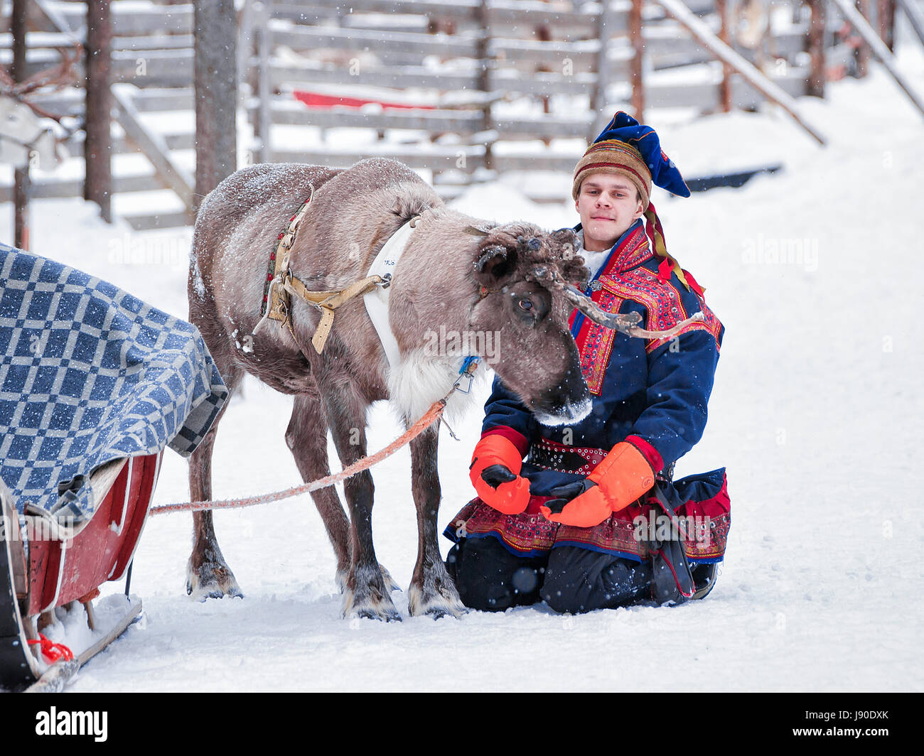 Rovaniemi, Finnland - 3. März 2017: Mann im traditionellen Saami Kostüm und das Rentier in Winter Bauernhof, Rovaniemi, Lappland, Finnland Stockfoto