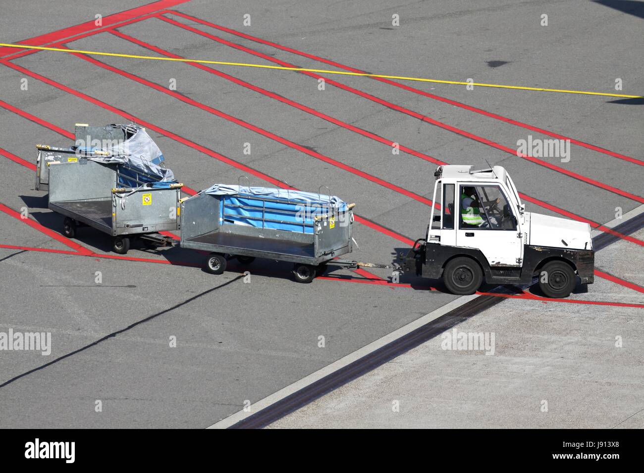 Flughafen-Schürze mit Gepäckwagen Stockfoto