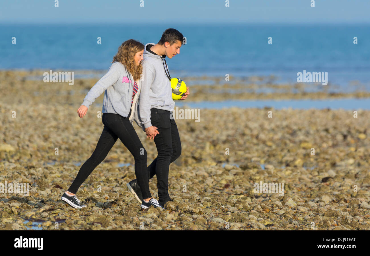 Junges Paar unter einem Abend gehen hand in hand am Strand entlang. Stockfoto