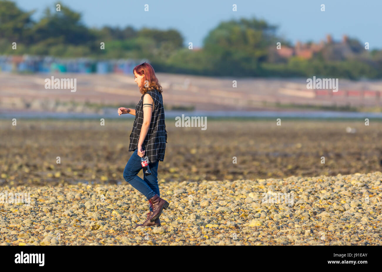 Junge Frau zu Fuß am Strand am späten Abend licht. Stockfoto