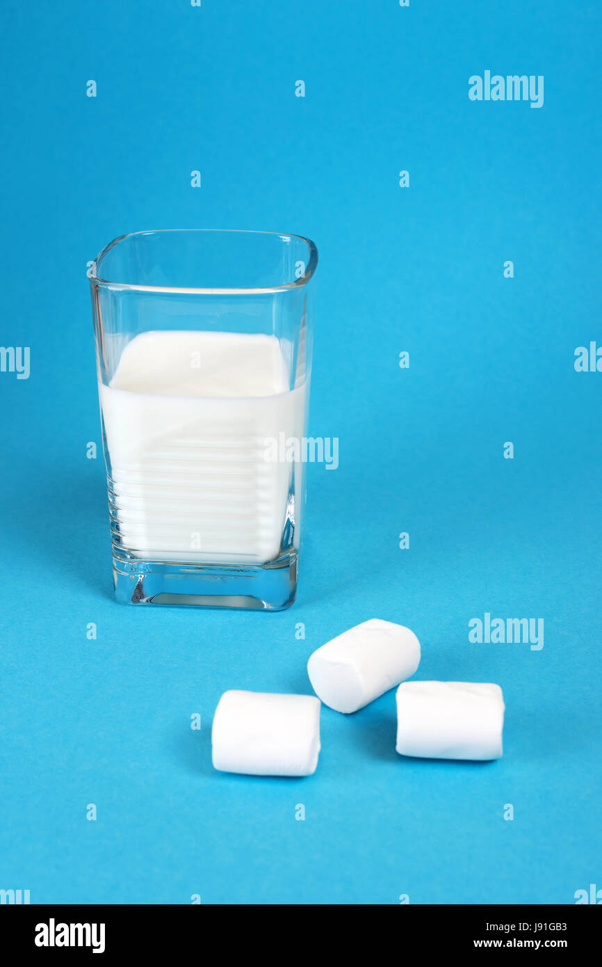 Glas Milch auf blauem Hintergrund mit süßen Marshmallows. Stockfoto