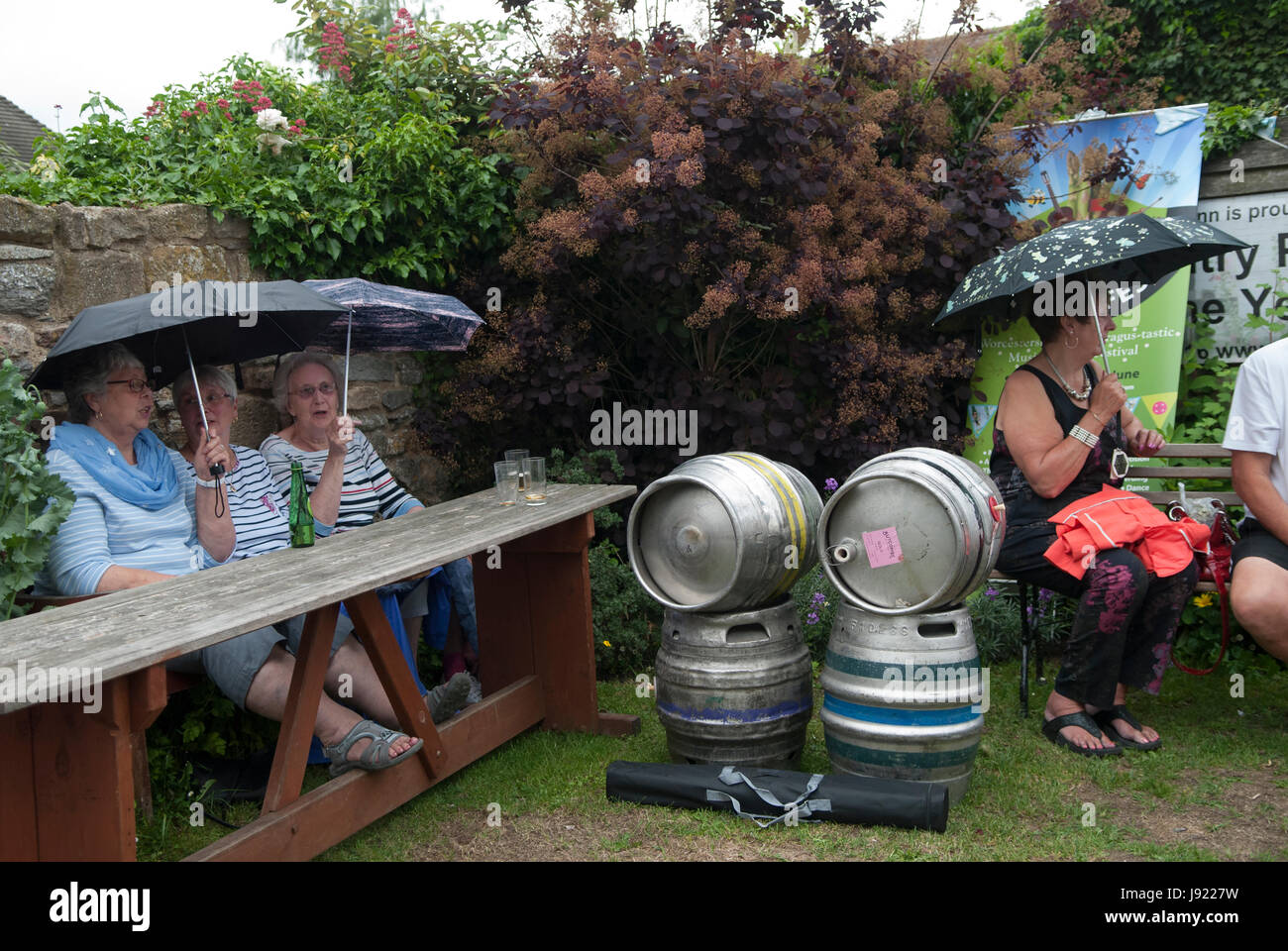 Regen regnet UK britisches nasses Wetter schlechtes Wetter Sommerwetter Leute, die unter Regenschirmen geschützt sind. Der Pub-Garten des Fleece Inn. Bretforton, Vale of Evesham, Worcestershire, 2017 2010er Jahre, UK HOMER SYKES Stockfoto