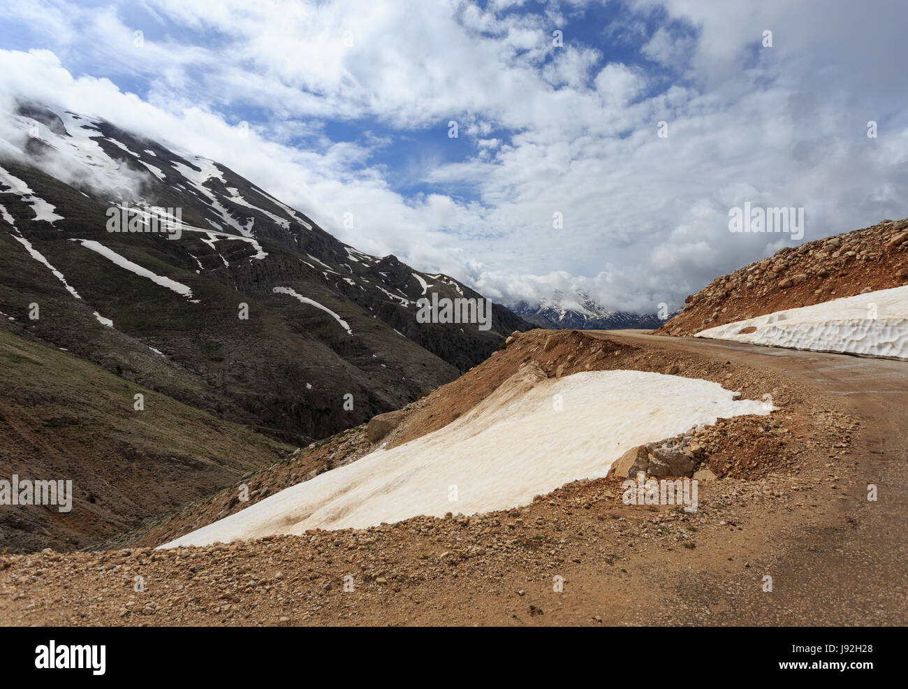 Horizontale schuss Berglandschaft mit Serpentinenstraße und Pisten durch schmelzenden Schnee und Wolken bedeckt Stockfoto