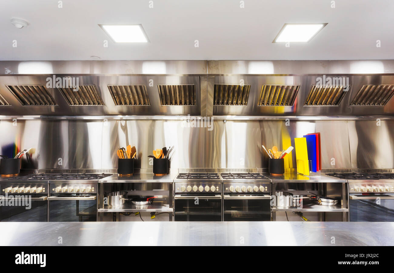 Moderne saubere ausgestattete Küche mit Edelstahl-Kochfeldern, Tabellen, Kochutensilien und Kleingeräte. Stockfoto