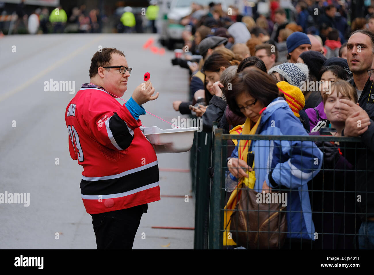 Vancouver, BC, Kanada. 11. November 2016. Ein freiwilliger Verkauf Mohnblumen während der Erinnerung-Tag Zeremonie am Platz des Sieges in der Innenstadt von Vancouver. Stockfoto