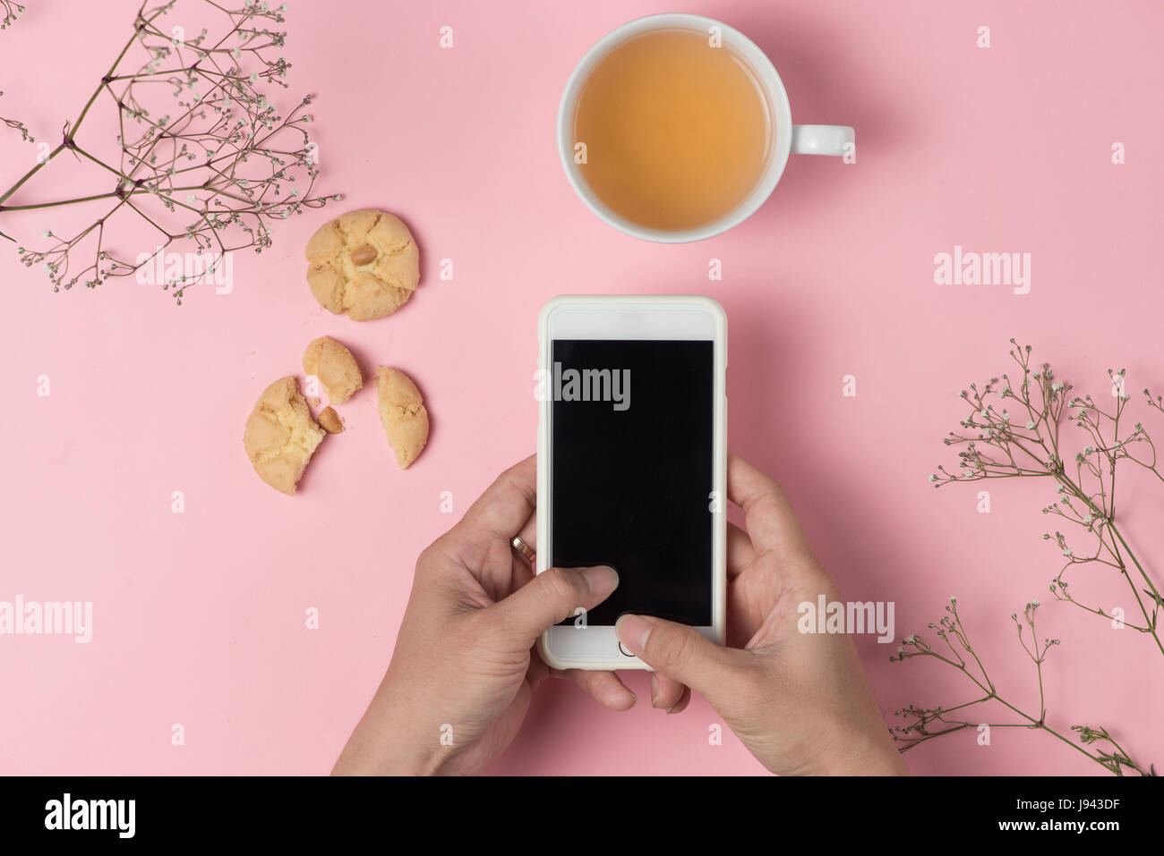 Hände des Mannes beim Trinken Tee und Essen Hafer Cookie Handy halten. Stockfoto