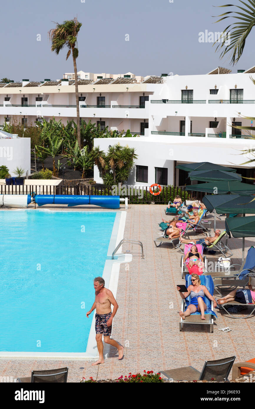 Menschen im Urlaub Sonnenbaden rund um einen Swimmingpool, Santa Rosa, Costa Teguise, Lanzarote, Kanarische Inseln, Europa Stockfoto