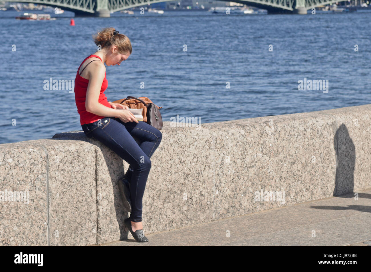 Blonde Mädchen lesen neben dem Fluss. Stockfoto