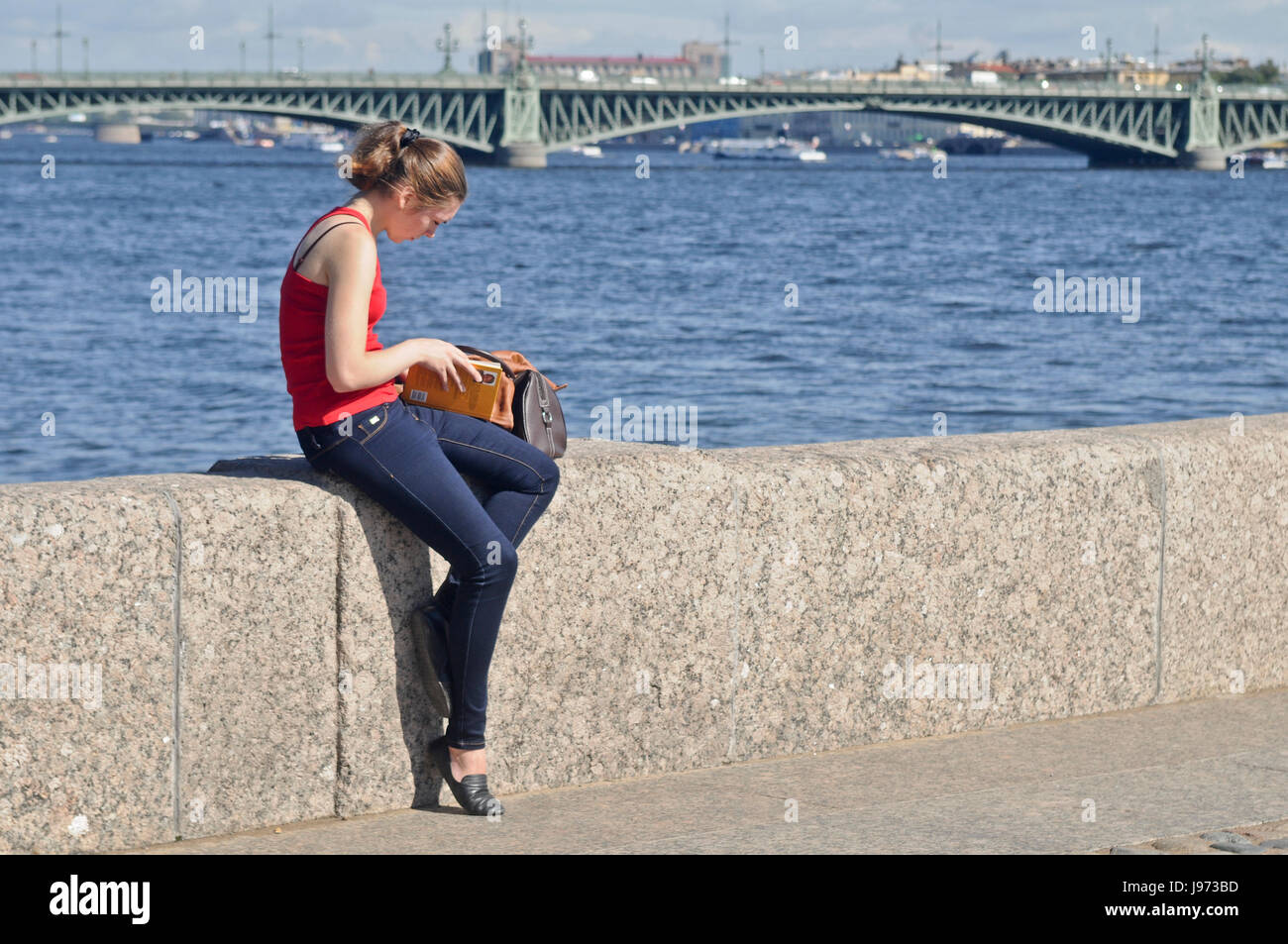 Blonde Mädchen lesen neben dem Fluss. Stockfoto