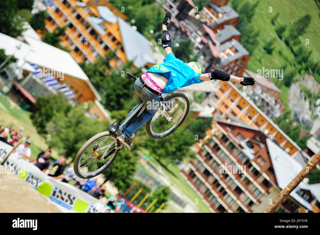 Mann springt mit seinem MTB während einer Freeride World Tour-Meisterschaft in Frankreich (hier im Dorf von "Deux Alpes") Stockfoto