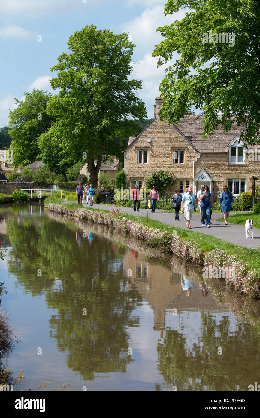 Touristen zu Fuß durch das hübsche Dorf von Lower Slaughter in Gloucestershire Stockfoto