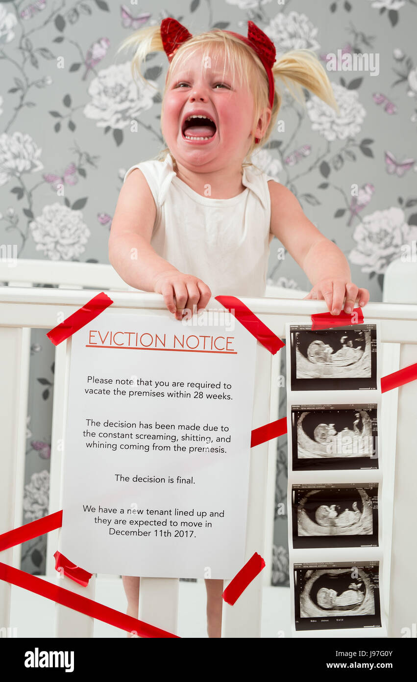 Lustige baby Ankündigung. Ein Kind stand auf, Babybett mit einem lustigen Vertreibung Nachricht an der Seite. Stockfoto