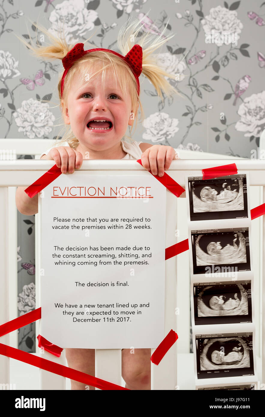 Lustige baby Ankündigung. Ein Kind stand auf, Babybett mit einem lustigen Vertreibung Nachricht an der Seite. Stockfoto