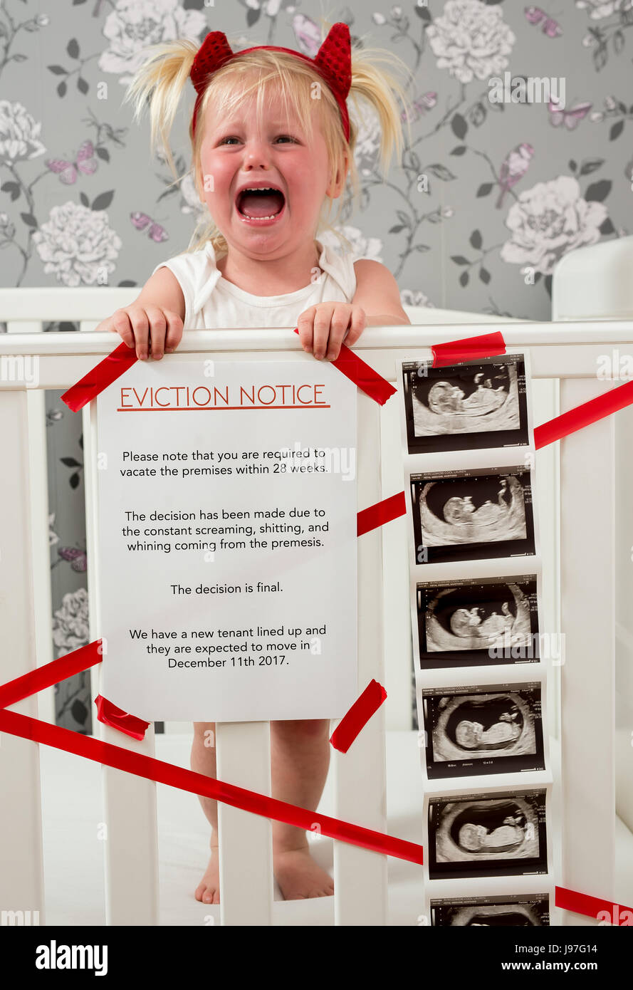 Lustige baby Ankündigung. Ein Kind stand auf, Babybett mit einem lustigen Vertreibung Nachricht an der Seite. Stockfoto