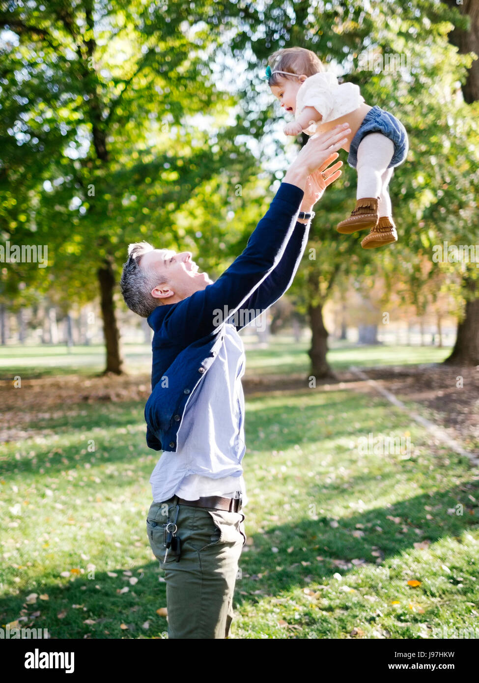 Vater warf Tochter (12-17 Monate) in Luft im park Stockfoto