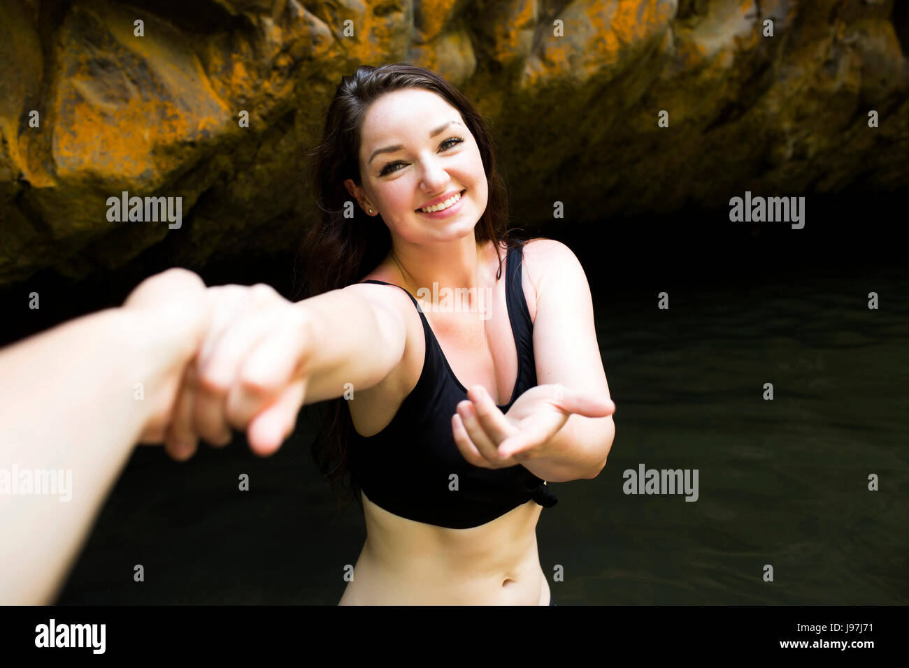 Frau von Wasser jemandes Hand haltend und Blick in die Kamera Stockfoto