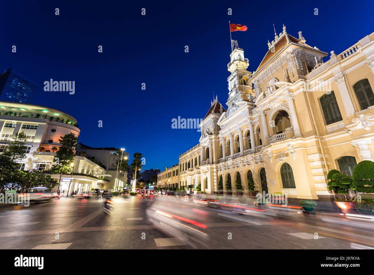 Motorräder in der Nacht vor der berühmten Volkskomitee Gebäude im Herzen der Innenstadt von Ho Chi Minh in Vietnam größte Stadt hetzen, Stockfoto