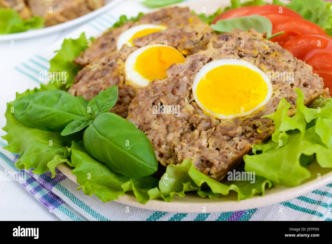 Hackbraten gefüllt gekochtes Ei mit frischen Tomaten und Salatblätter ...