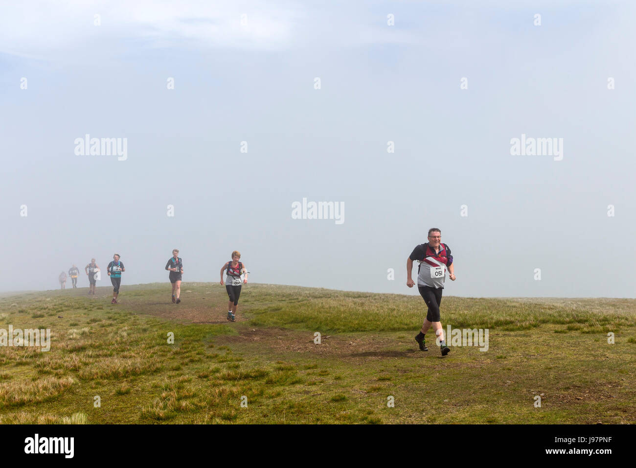 Läufer, die Teilnahme an der Lakelandpoeten und der Dodds fiel Rennen erscheinen aus dem Nebel auf dem Gipfel des Clough Head, Lake District, Cumbria, UK Stockfoto