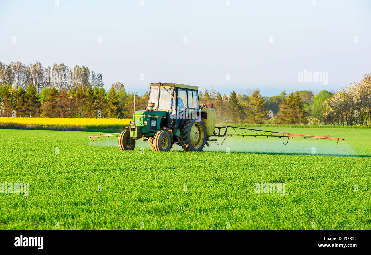 Schonen, Schweden - 18. Mai 2017: Umwelt Dokumentarfilm. Landwirt mit Traktor John Deere 2140, wenn Pestizide auf Feld abends zu verbreiten. Stockfoto