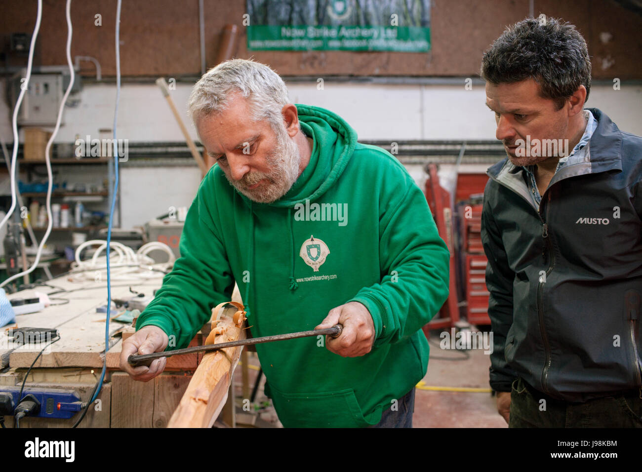 Rob und Tom verwenden ein Ziehmesser um zu beginnen, Gestaltung der Eibe Langbogen. Stockfoto