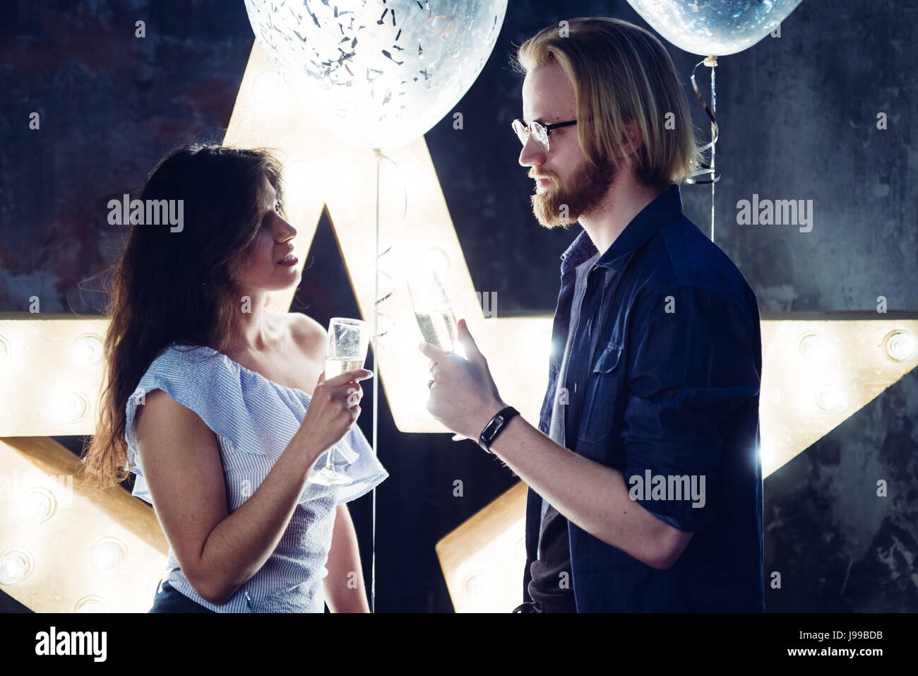 Junger kurzz feiert ihre Liebe Toasten mit Sektglas mit einer Hintergrundbeleuchtung Hollywood Stil Nachbearbeitung verwendet, um die Stimmung und Töne o erhöhen Stockfoto