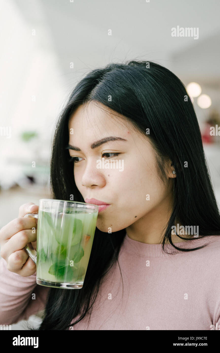 Junge asiatische Mädchen trinken grünen frischen Tee schauen und genießen Sie ihr Leben Stockfoto