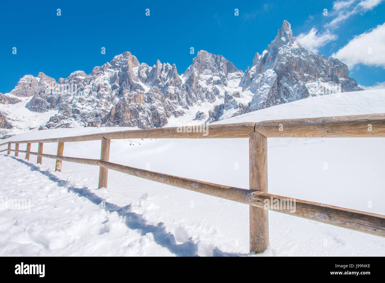 Majestätische Dolomiten in all ihrer Pracht in Schnee bedeckt, mit blauem Himmel und einem hölzernen Zaun im Vordergrund. Stockfoto