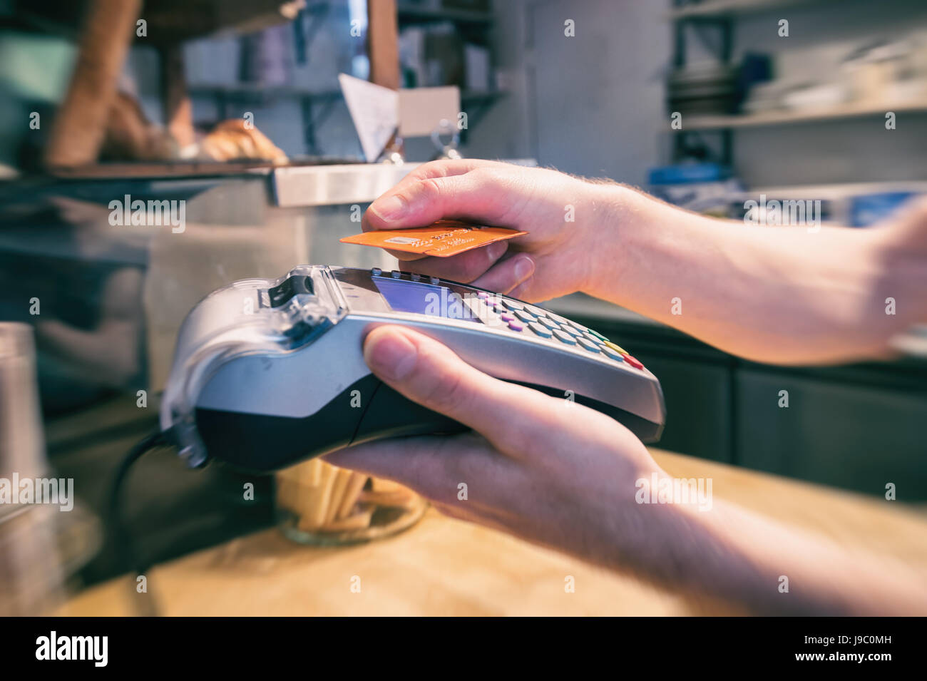 Nahaufnahme einer Hand mit einer kontaktlosen Kreditkarte terminal bezahlen Stockfoto