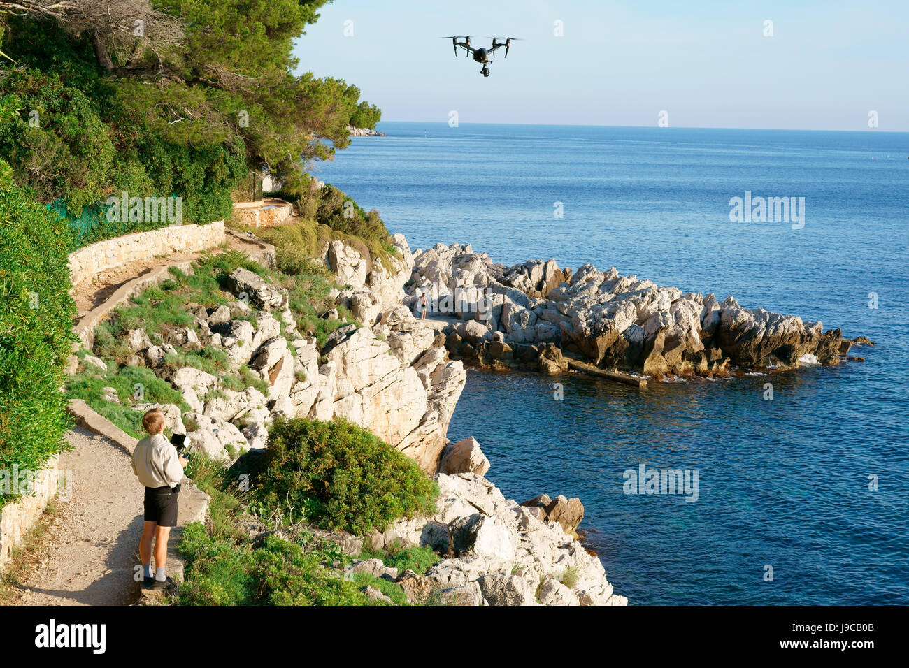 Mann, der ein unbemanntes Luftfahrzeug (Drohne) fliegt. Saint-Jean-Cap-Ferrat, Französische Riviera, Provence-Alpes-Côte d'Azur, Frankreich. Stockfoto