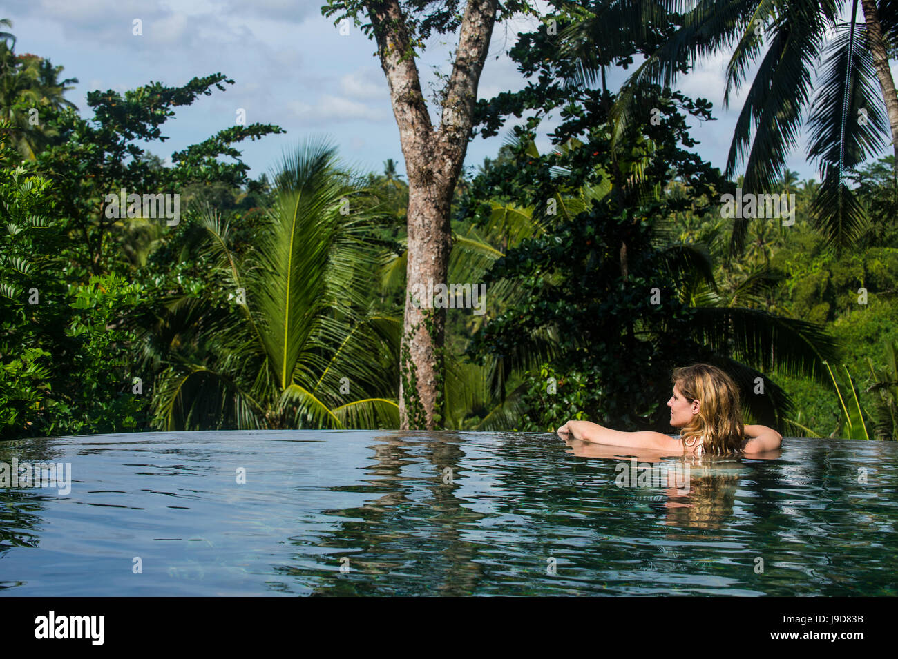 Frau genießen einen überlaufenden Pool über einem Tal im Kamandalu Ubud Resort, Ubud, Bali, Indonesien, Südostasien, Asien Stockfoto